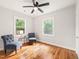 Sunlit bedroom with hardwood floors, two blue chairs, and two windows at 109 Davidson Ave, Durham, NC 27704