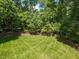 A lush backyard featuring a wooden fence and manicured lawn surrounded by mature trees at 124 Creekvista Dr, Holly Springs, NC 27540