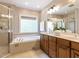Bright bathroom with a soaking tub, dual sinks, tile floor, and a glass-enclosed shower at 124 Creekvista Dr, Holly Springs, NC 27540