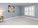 Neutral bedroom with a large floral art piece and bright window with white plantation shutters at 124 Creekvista Dr, Holly Springs, NC 27540