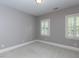 Bright bedroom with neutral paint, carpet, white trim, and two windows with plantation shutters at 124 Creekvista Dr, Holly Springs, NC 27540