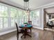 Sunlit breakfast nook with a round wood table and chairs under modern pendant lighting by bright windows at 124 Creekvista Dr, Holly Springs, NC 27540