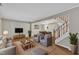 Bright living room featuring modern furniture, wood floors, and staircase to second floor at 134 Riverwalk Cir, Cary, NC 27511
