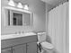 Modern bathroom features a gray vanity, a white toilet, and a shower-tub combo with a white curtain at 1503 Laughridge Dr, Cary, NC 27511