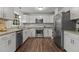A well-lit kitchen featuring stainless steel appliances, granite countertops, and white cabinetry at 1503 Laughridge Dr, Cary, NC 27511