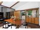 Open dining room with a wooden table, unique paneling, and a view of the kitchen at 1604 Pinecrest Rd, Durham, NC 27705