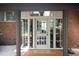 An inviting entryway featuring a tiled floor, glass paneled door and sidelights, and brick accents at 1604 Pinecrest Rd, Durham, NC 27705