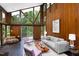 A well-lit living room featuring wood paneling, large windows with lush exterior views, and modern furnishings at 1604 Pinecrest Rd, Durham, NC 27705