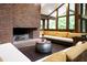 Cozy living room with a brick fireplace and large windows overlooking a lush, green outdoor space at 1604 Pinecrest Rd, Durham, NC 27705