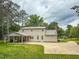 Spacious backyard with a two-story home featuring a covered parking area and a concrete driveway at 20 Banbury Ct, Roxboro, NC 27573