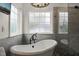 Close up on a bathtub in a bathroom featuring light grey tiling, a window, and a glass shower, providing a spa like feel at 2000 Katesbridge Ln, Raleigh, NC 27614
