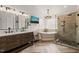 Bright bathroom featuring double sinks, soaking tub, a tiled shower, and herringbone flooring, providing a luxurious experience at 2000 Katesbridge Ln, Raleigh, NC 27614