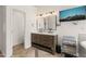 Well-lit bathroom with double sinks, warm-toned wooden cabinetry, a TV and stylish herringbone flooring, providing luxury and convenience at 2000 Katesbridge Ln, Raleigh, NC 27614