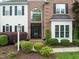 Close-up of the home's entrance, showcasing a black front door, sidelights, and manicured landscaping at 2000 Katesbridge Ln, Raleigh, NC 27614