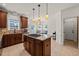 Spacious kitchen with dark wood cabinets, an island with a cooktop, and pendant lighting, with natural light at 2000 Katesbridge Ln, Raleigh, NC 27614