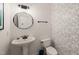 Stylish powder room with a pedestal sink, toilet, decorative wallpaper, and modern fixtures at 2000 Katesbridge Ln, Raleigh, NC 27614