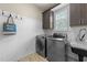 Bright laundry room featuring modern washer, dryer, utility sink and convenient upper storage at 205 Benwell Ct, Cary, NC 27519