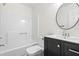 Simple bathroom featuring a black vanity, tub/shower combo, and round mirror at 214 Wax Myrtle Ct, Cary, NC 27513