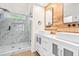 Modern bathroom featuring double vanities, wood accent wall, and glass walk-in shower at 214 Wax Myrtle Ct, Cary, NC 27513