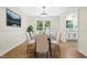 Bright dining room featuring a glass table, six chairs, natural light, and a seamless flow to the kitchen, ideal for gatherings at 214 Wax Myrtle Ct, Cary, NC 27513