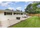 Side view of the backyard with grassy lawn, patio with two seating areas, and exterior white painted brick at 2205 W Carver St, Durham, NC 27705