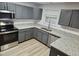 Modern kitchen featuring stainless steel appliances, gray cabinets, granite countertops, and wood-look flooring at 225 Virens Drive, Cary, NC 27511