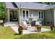 Cozy backyard patio with string lights, an outdoor fireplace, seating, and rear porch access at 2409 New Hope Church Rd, Chapel Hill, NC 27514