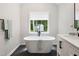 Spa-like bathroom with a freestanding tub, a large window, and sleek tile floors at 2409 New Hope Church Rd, Chapel Hill, NC 27514