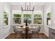 Cozy dining area bathed in natural light features modern lighting and a view of the wooded lot at 2409 New Hope Church Rd, Chapel Hill, NC 27514