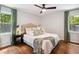 Cozy bedroom featuring a ceiling fan, two windows, and warm hardwood floors at 2409 New Hope Church Rd, Chapel Hill, NC 27514