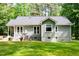Back of a home with a patio area, string lights, mature trees, and green lawn at 2409 New Hope Church Rd, Chapel Hill, NC 27514