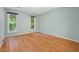 This bedroom has hardwood floors and light green walls with a view of nature through two windows at 2525 Buxton Ct, Chapel Hill, NC 27514