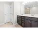 Bathroom featuring double sink vanity with dark cabinets and a view of the tile shower through the mirror at 2622 Perthshire Ln, Fuquay Varina, NC 27526