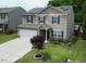 Charming two-story home with vinyl siding, blue shutters, attached two car garage, manicured lawn, and solar panels at 2622 Perthshire Ln, Fuquay Varina, NC 27526
