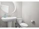 Clean powder room featuring a pedestal sink, round mirror, and a white toilet at 2622 Perthshire Ln, Fuquay Varina, NC 27526