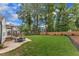 A well-manicured backyard featuring a stone patio, dining set, and lush lawn surrounded by mature trees at 2721 Dahlgreen Rd, Raleigh, NC 27615