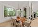 Bright dining room features a wood table, modern light fixture, and floor-to-ceiling windows with views of the surrounding forest at 2721 Silver Stirrup Ln, Apex, NC 27502