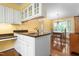 Kitchen area with white cabinetry, countertop workspace, and a sink with a view into the sunny dining room at 3123 Amherst Ave, Burlington, NC 27215