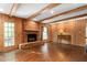 Cozy living room featuring a brick fireplace, wood paneling, and large windows overlooking the backyard at 3123 Amherst Ave, Burlington, NC 27215