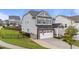 Side view of a gray two-story home with a two-car garage, dark shutters, and a well-maintained lawn with a black fence at 348 Golf Vista Trl, Holly Springs, NC 27540