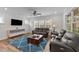 Cozy living room featuring hardwood floors, a ceiling fan, and comfortable seating with lots of natural light at 348 Golf Vista Trl, Holly Springs, NC 27540