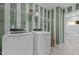 Well-equipped laundry room with a front-load washer, dryer, shelving, and elegant striped walls at 3625 Bailey Lake Dr, Fuquay Varina, NC 27526