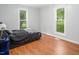 Bedroom features two windows with scenic views, wood floors, and a comfortable bed at 3627 Nc 57, Hillsborough, NC 27278