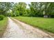 Long gravel driveway leading to a home, surrounded by green lawns and mature trees at 3627 Nc 57, Hillsborough, NC 27278