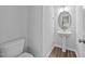 Stylish half bathroom featuring pedestal sink with oval mirror and wood-look flooring at 380 Garden Vine Trl, Raleigh, NC 27610