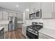 Modern kitchen featuring gray cabinetry, stainless steel appliances and tile backsplash at 380 Garden Vine Trl, Raleigh, NC 27610