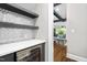 Stylish wet bar with wine fridge, mosaic backsplash, and modern shelving at 3829 Westbury Lake Dr, Raleigh, NC 27603