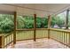 Covered back porch with wooden railing looks out to the backyard and trees at 4420 W River Rd, Franklinton, NC 27525