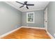 Cozy bedroom featuring hardwood floors, gray walls, white trim, a modern ceiling fan and a large window at 4420 W River Rd, Franklinton, NC 27525