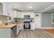 Galley kitchen featuring white cabinets, butcher block countertops, stainless steel appliances, and wood-look vinyl flooring at 4420 W River Rd, Franklinton, NC 27525